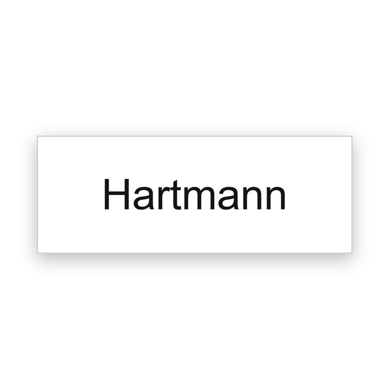 Rechteckiges weißes Klingelschild mit schwarzer Gravur, eine Zeile mit dem Namen Hartmann