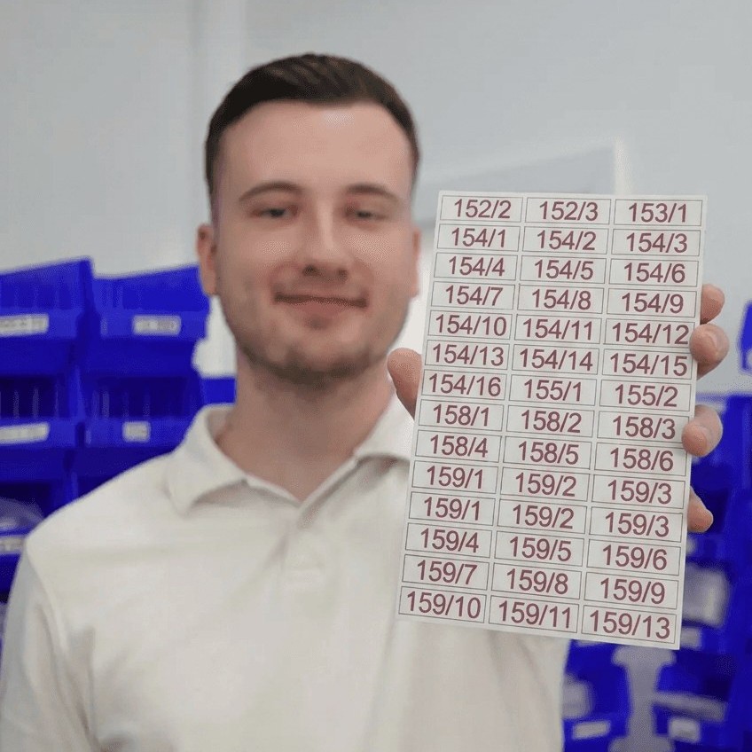 Julian in der Werkstatt mit einem Bogen gravierter Schilder