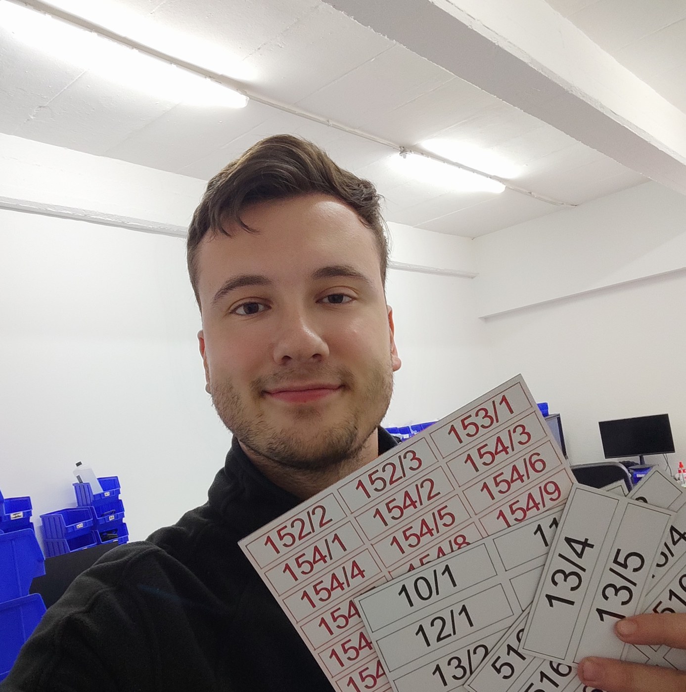 Julian hält fertig beschriftete Schilderbögen in der Werkstatt